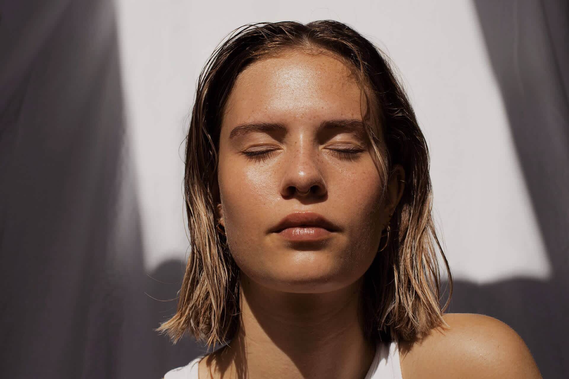 Close up shot of woman's face and skin under sunlight with short hair