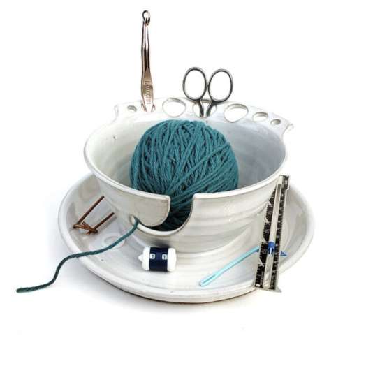 Hand-thrown cream colored stoneware bowl-and-caddy combo with blue yarn and knitting tools