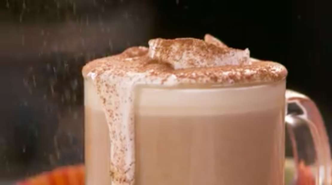 A pumpkin spice latte in a glass mug