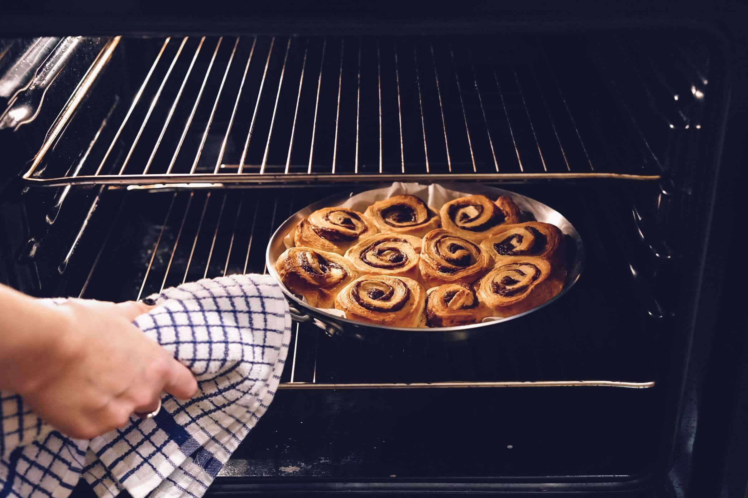 Woman baking crispy pastry dough in oven
