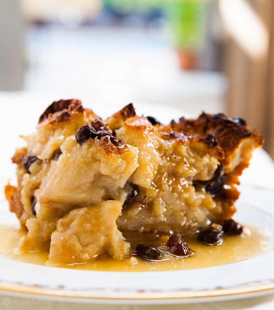 A 
piece of bread pudding covered in bourbon sauce served on a plate