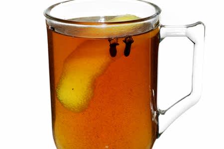 Glass filled with ginger hot toddy with lemon peel 