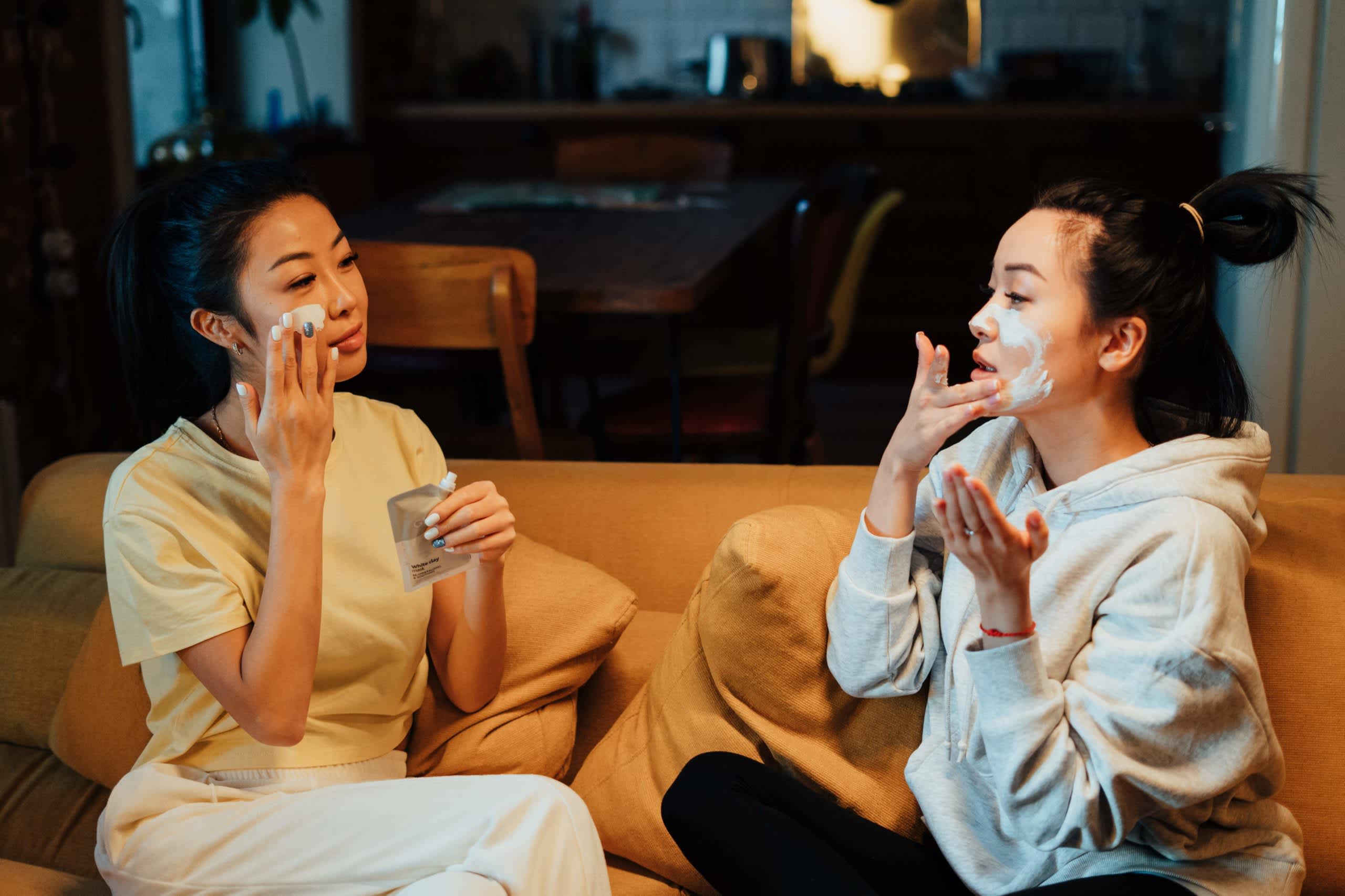 Women on a couch applying skin care creams