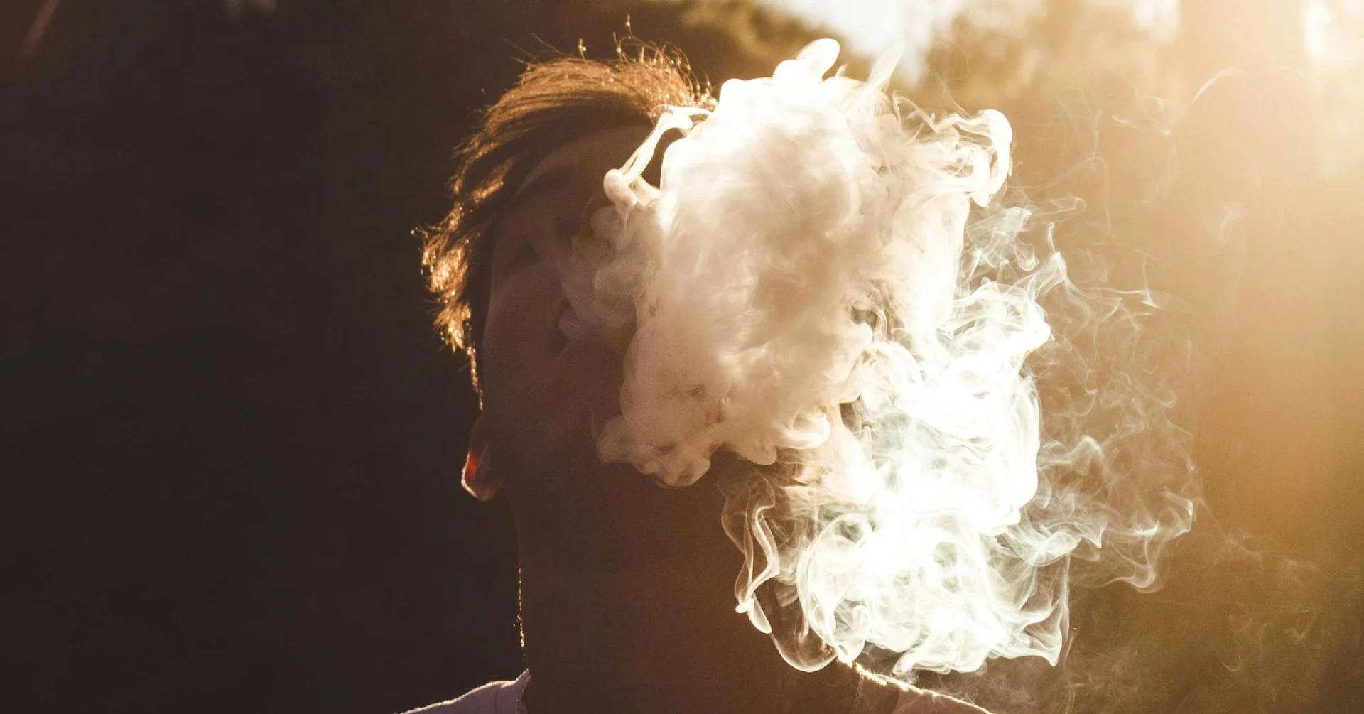 Jeune homme masqué par un nuage de fumée de vapoteuse.