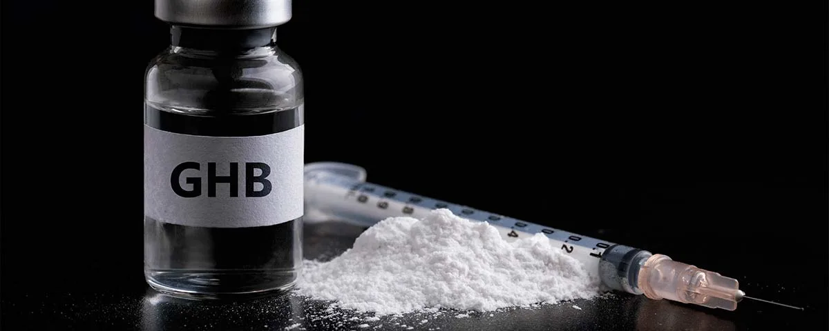Flacon avec étiquette portant la mention GHB à côté de poudre blanche.