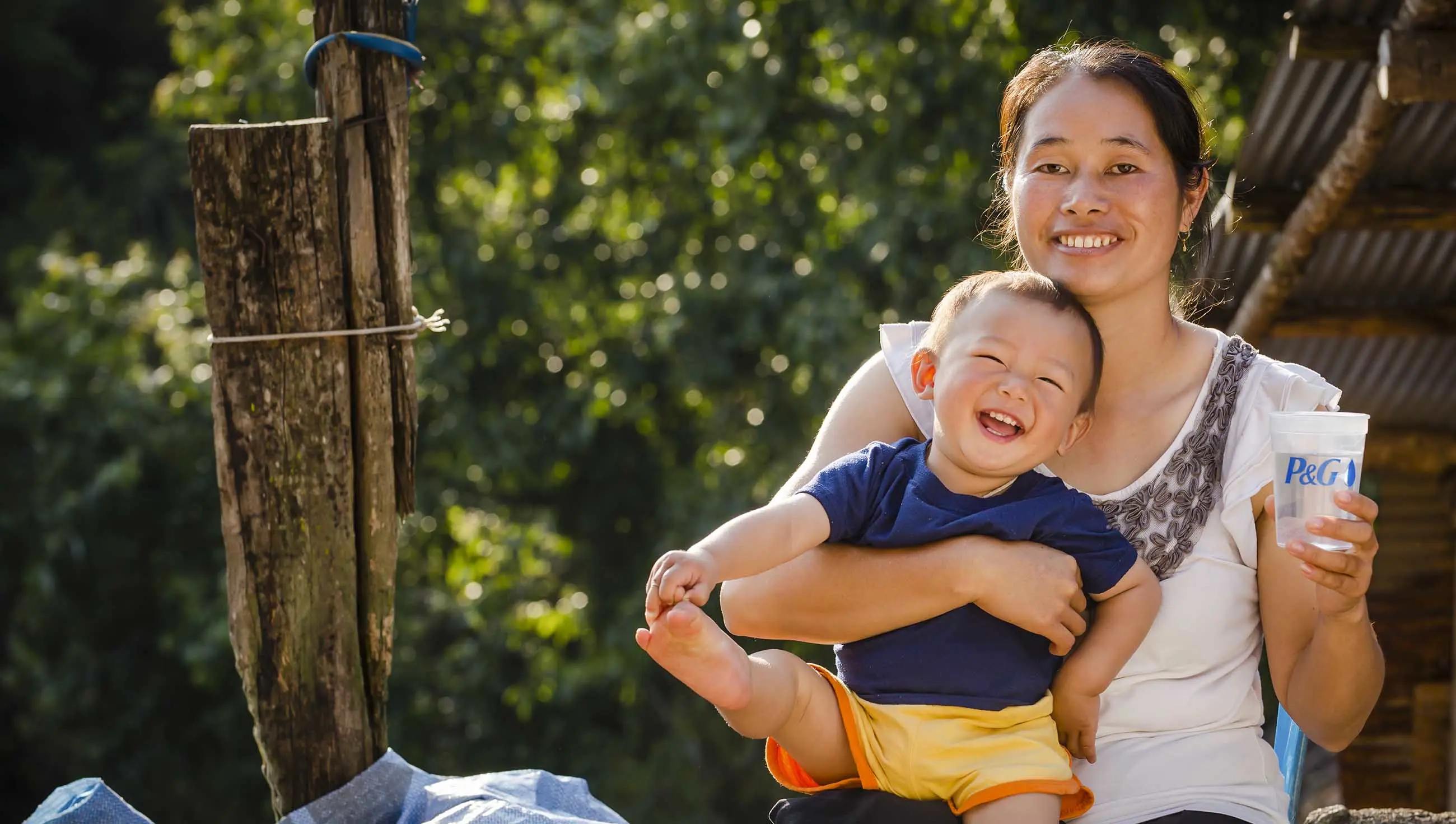 Mulher segurando um bebê sorridente e um copo de água purificada