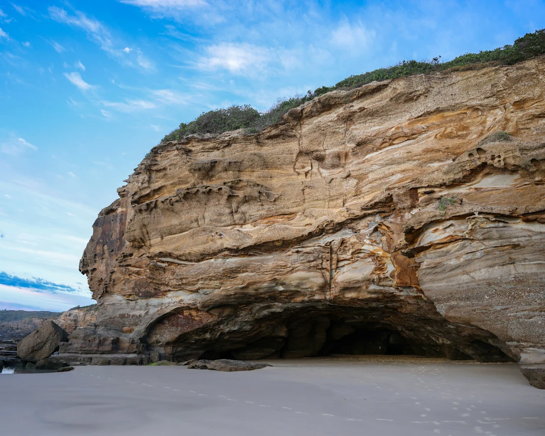 A coastal cliff stands against a blue sky.