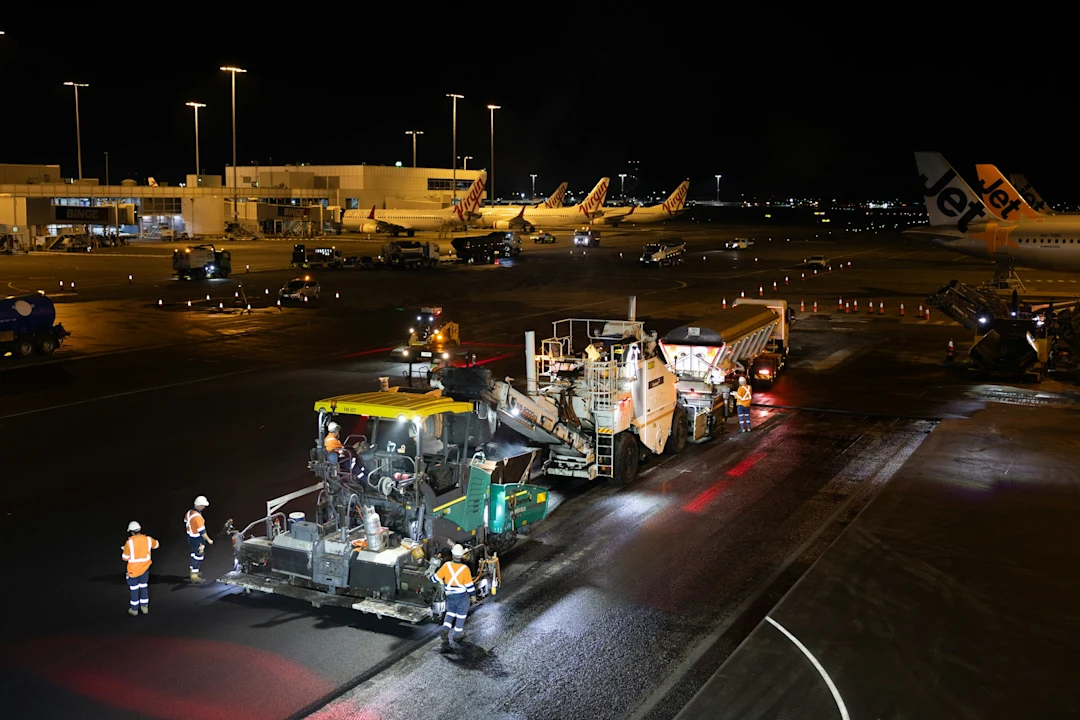 Airport tarmac resurfacing work at night with machinery and machinery