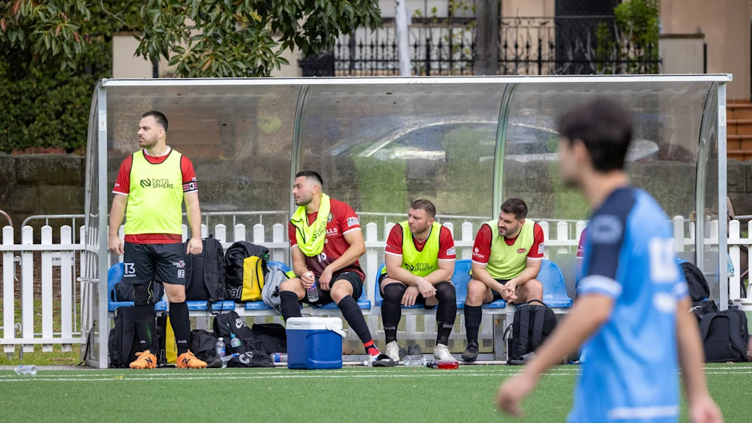 Soccer players sitting on the bench during a game.