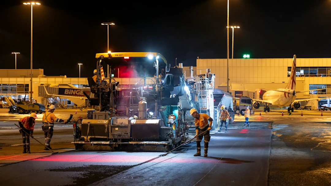 Construction workers paving a road at night