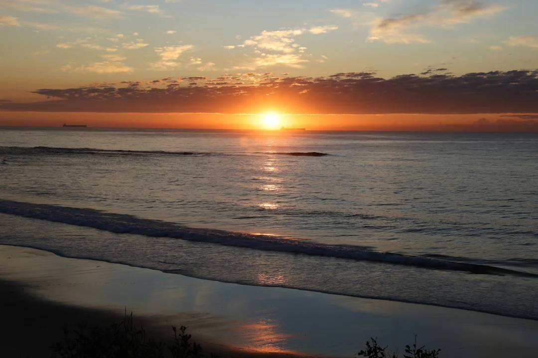 Sunrise over the calm ocean with reflections.
