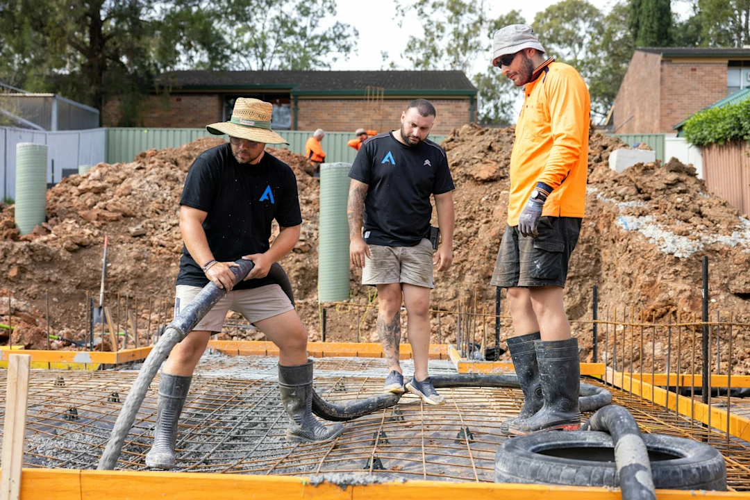 Construction workers are pouring concrete on a foundation.
