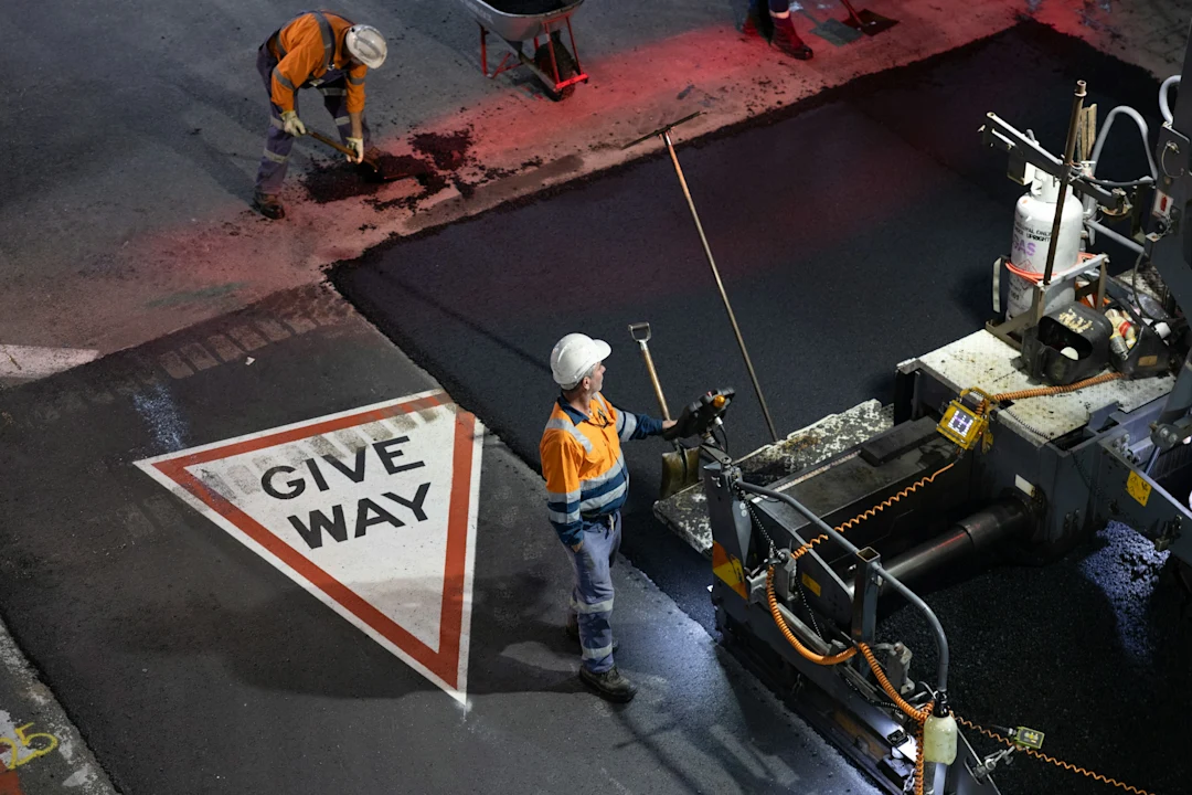 Workers paving a road with asphalt and asphalt machine.