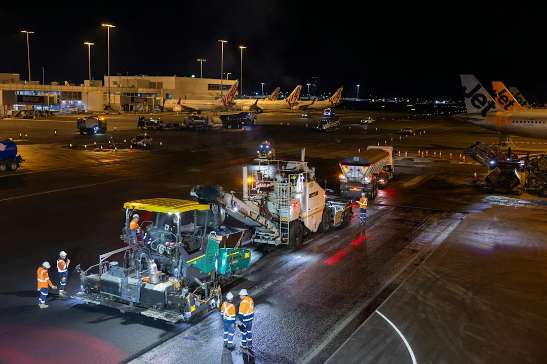 Airport runway resurfacing at night with heavy machinery
