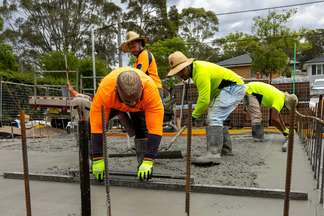 Construction workers pouring and leveling concrete.