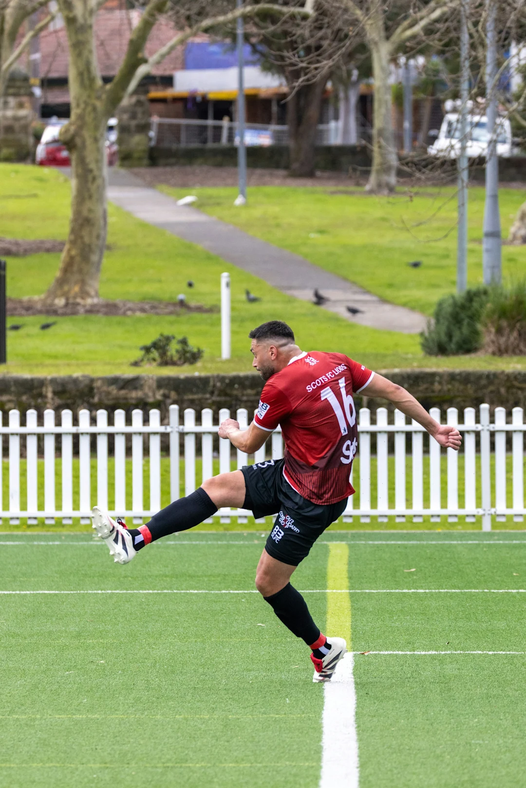 Soccer player in red jersey kicks ball on field.