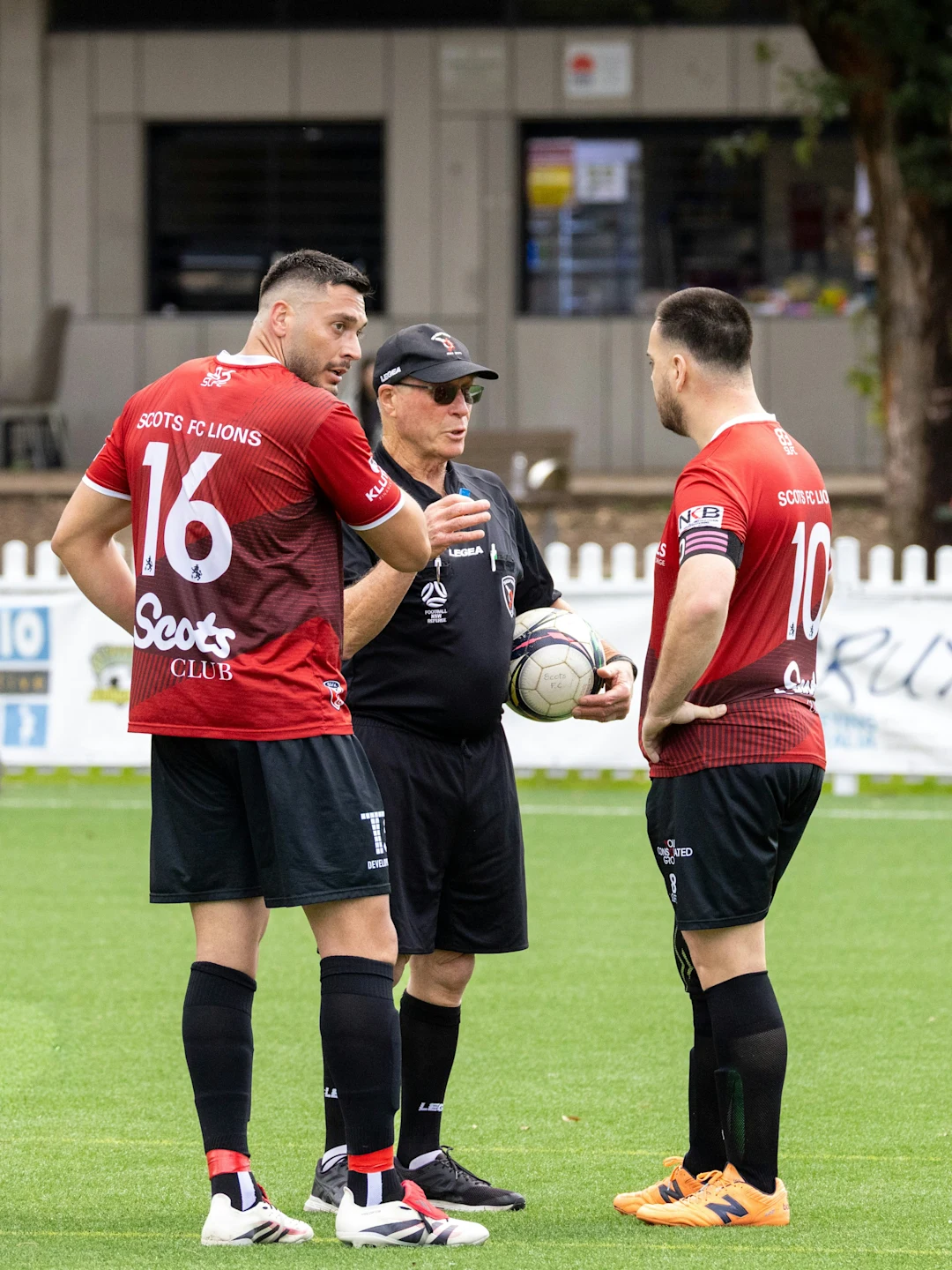 Soccer referee talks to two players on field