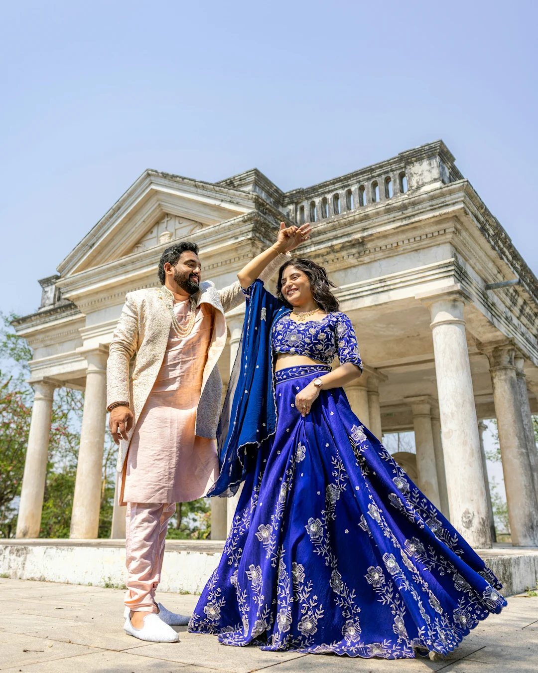 Couple in traditional indian attire posing near ancient ruins