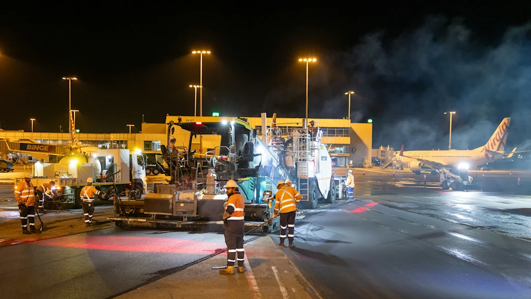 Airport tarmac crew works on asphalt at night.