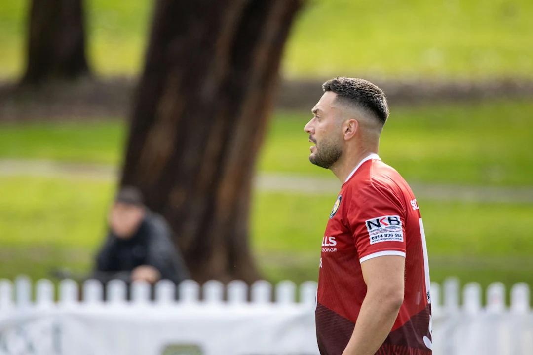 Man in red jersey looking away on a field.