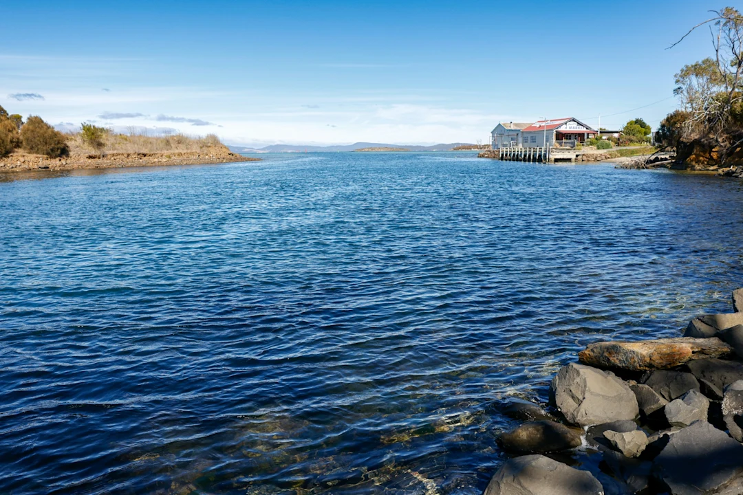 Calm blue water leads to a building on shore.