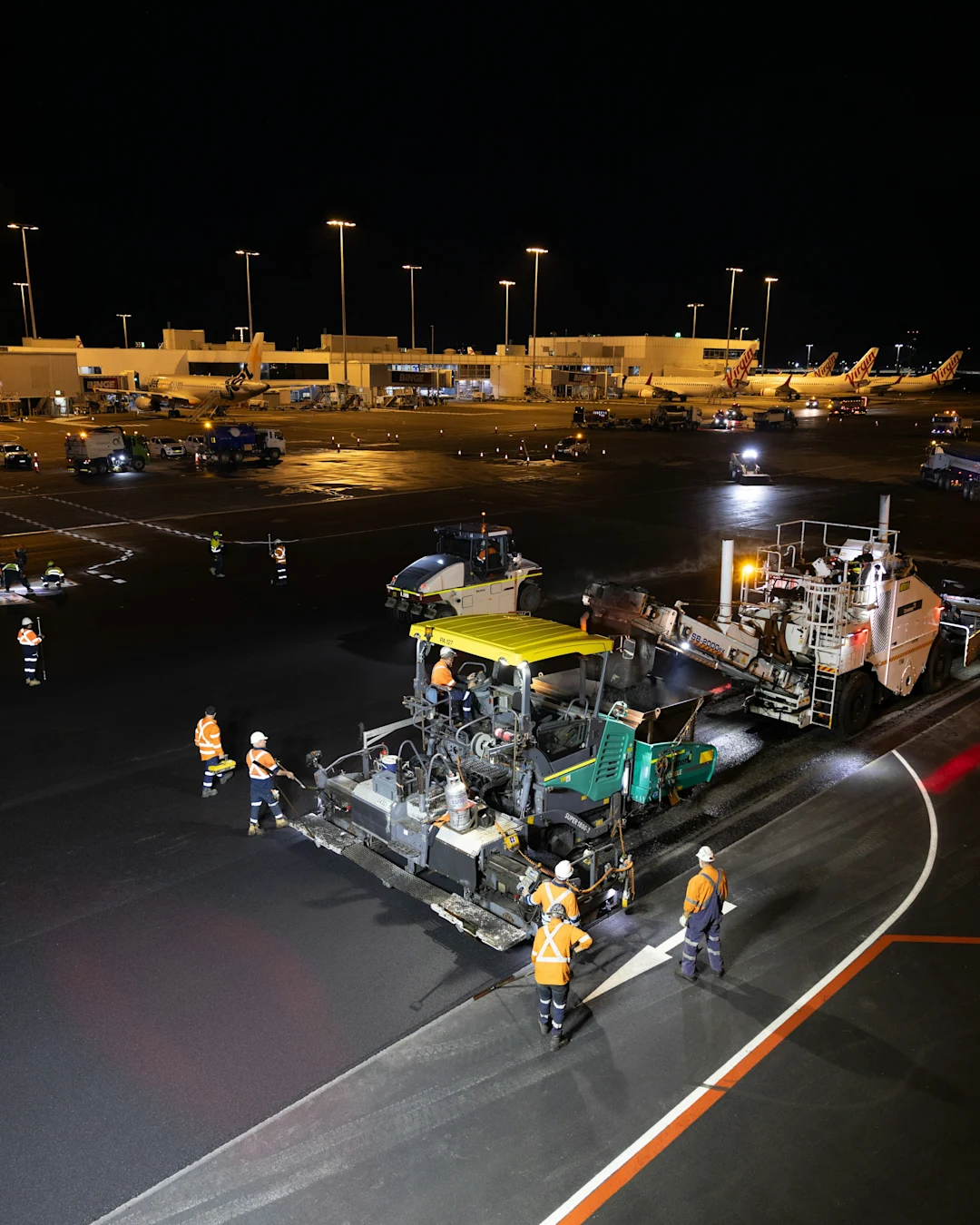 Construction workers repaving airport tarmac at night