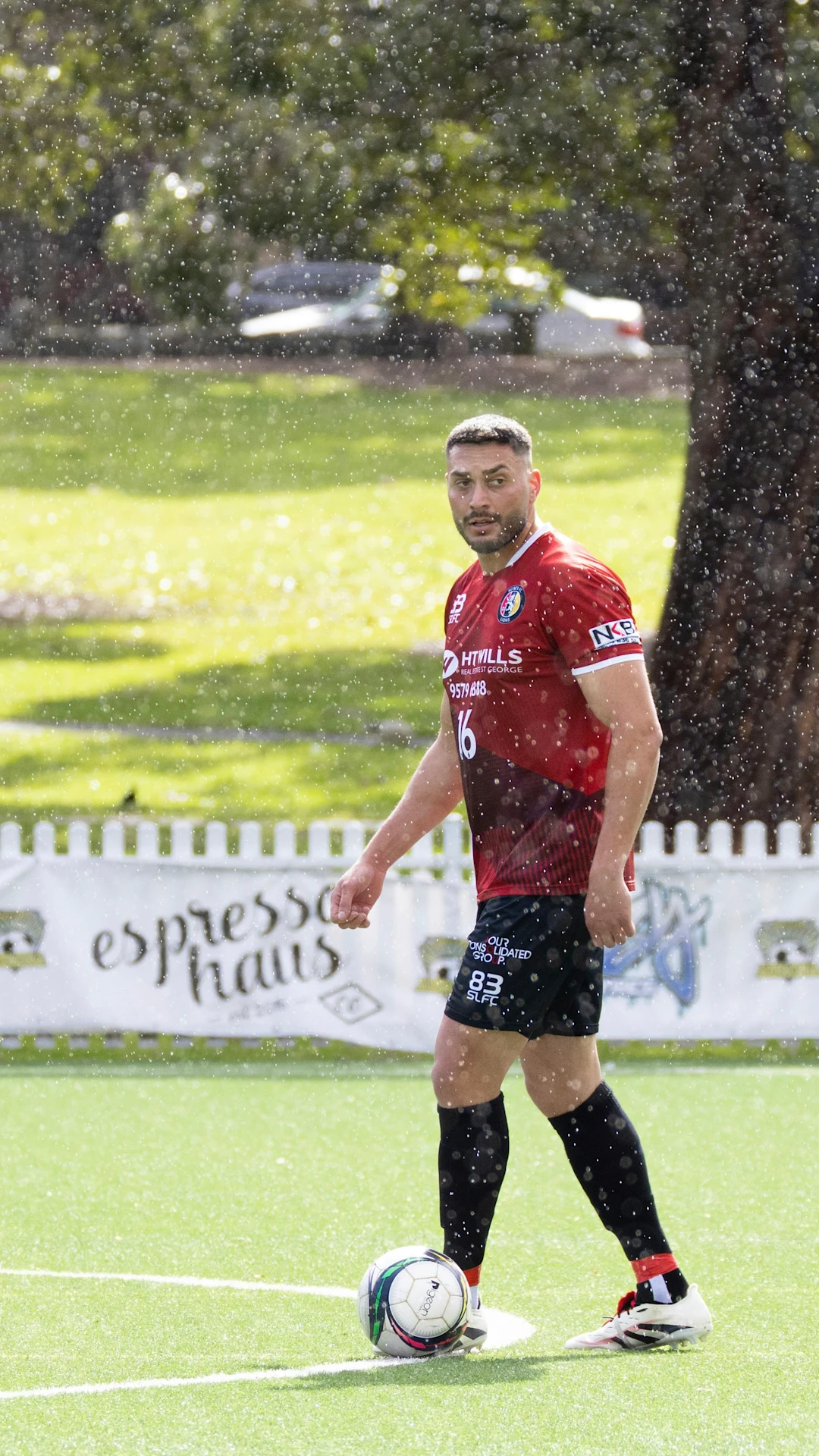 Soccer player in red jersey on field in rain
