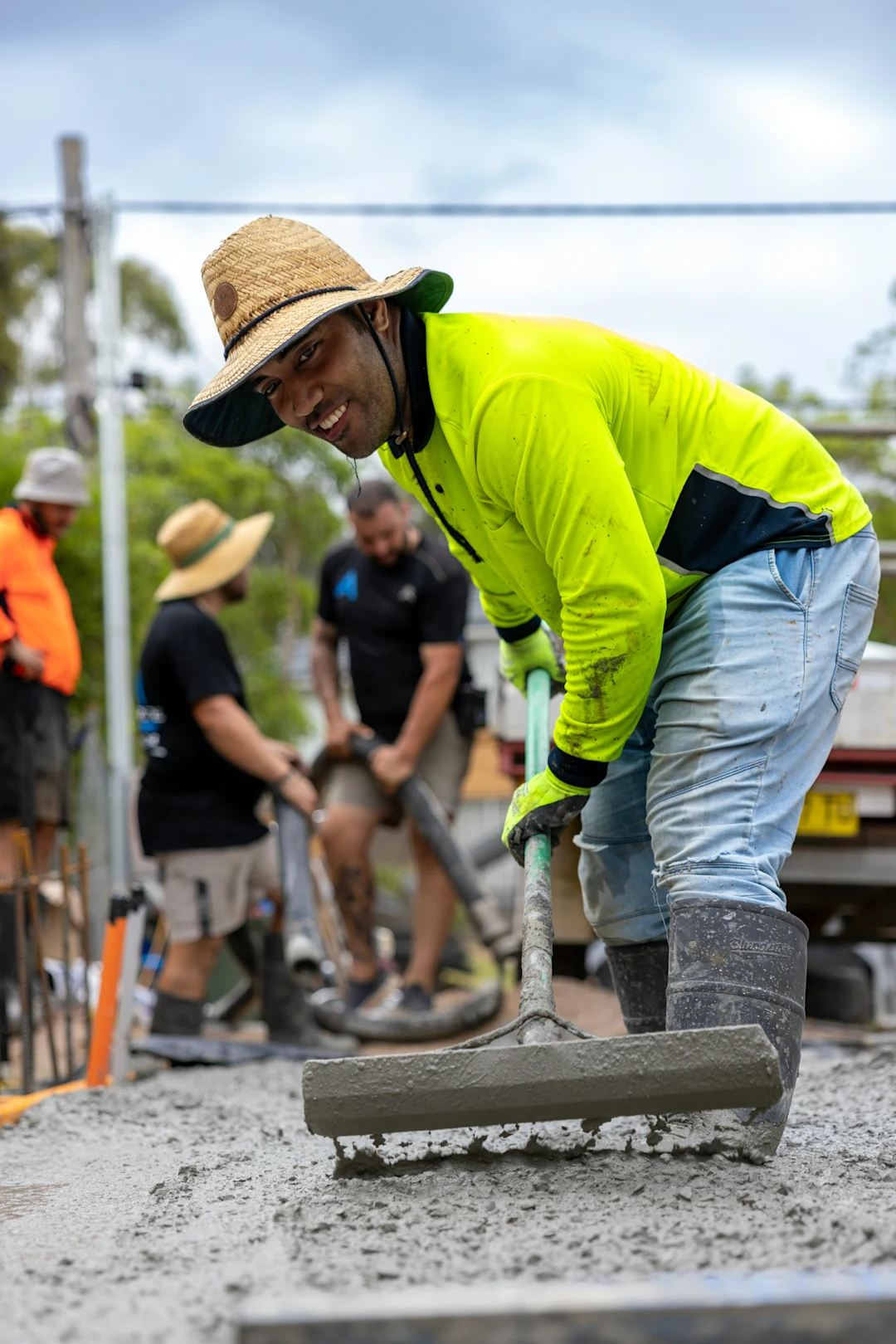 Worker leveling concrete with a rake on a construction site.