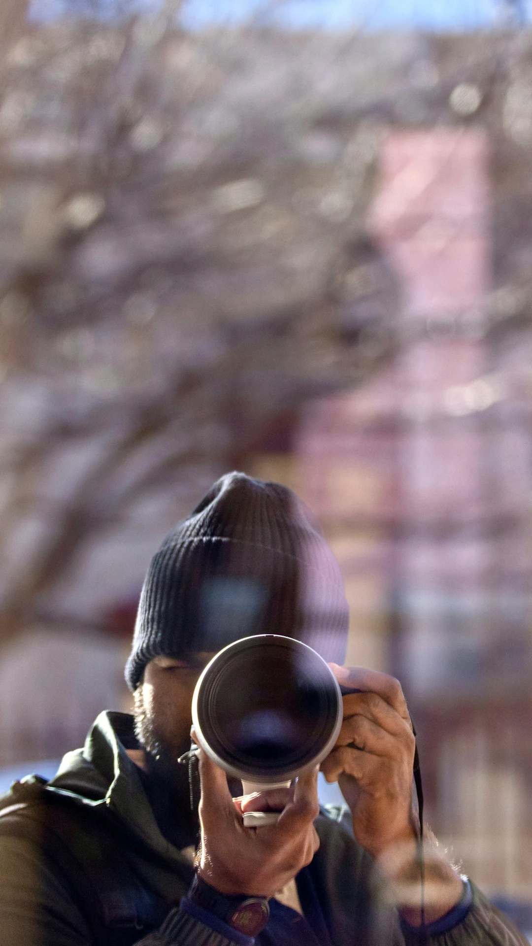 Man in beanie taking a picture with a camera.