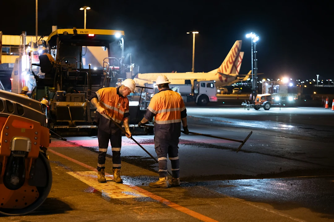 Workers paving an airport runway at night