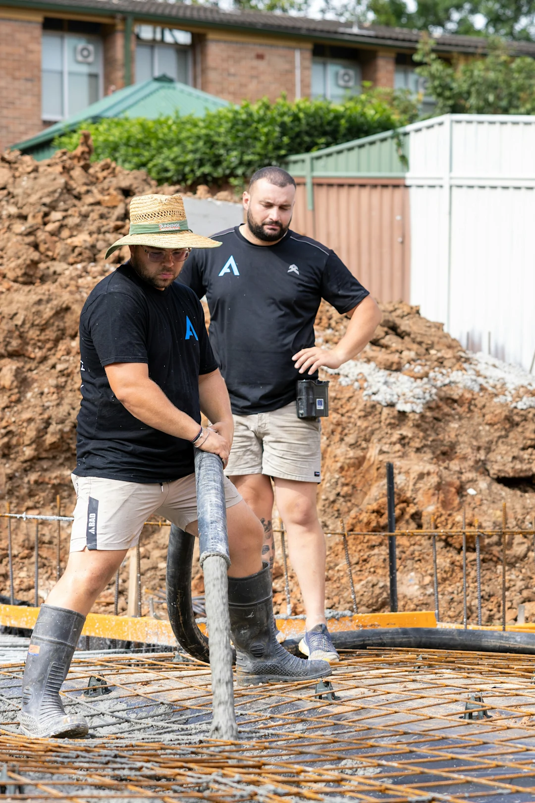 Construction workers pour concrete on a building foundation.