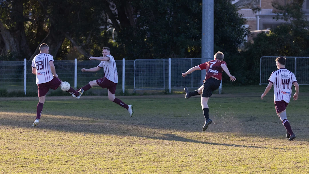 Men playing soccer on a grassy field during daytime.