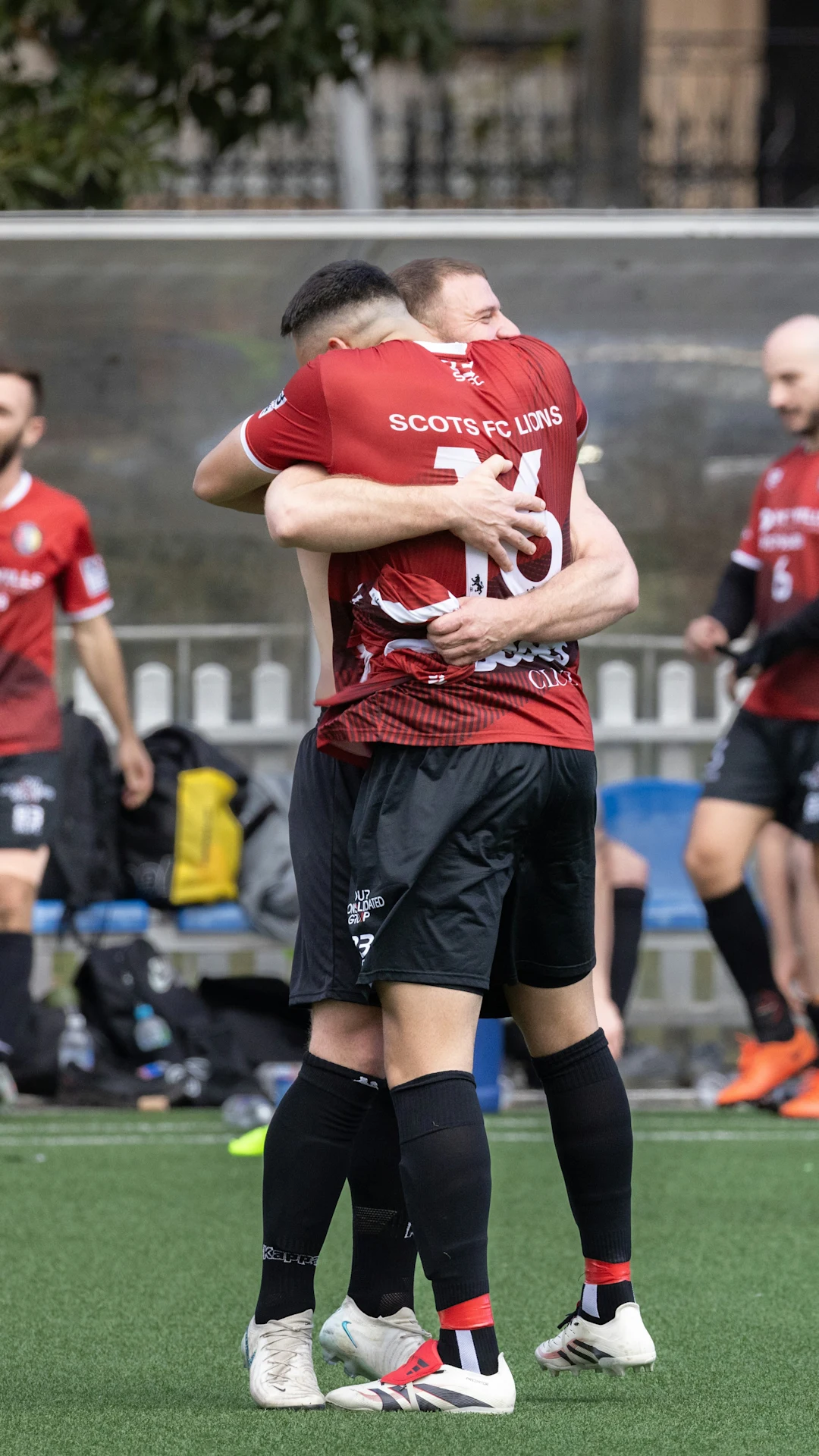 Two soccer players hugging on a field