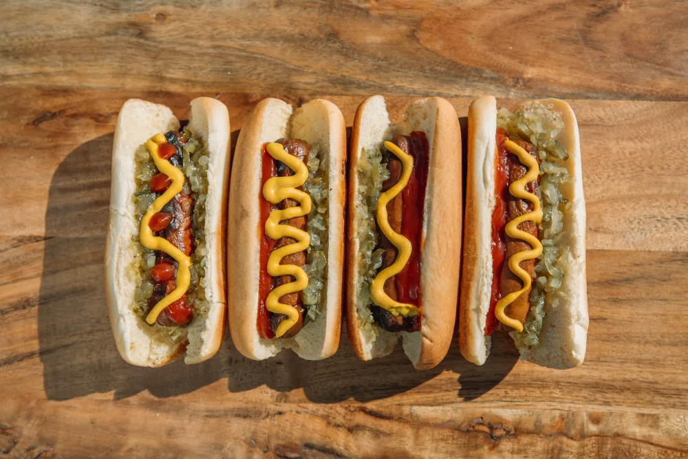 Four hot dogs with cucumber, mustard and ketchup
