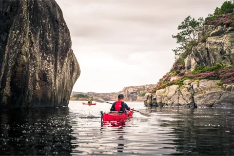 A man paddling in a red kayak
