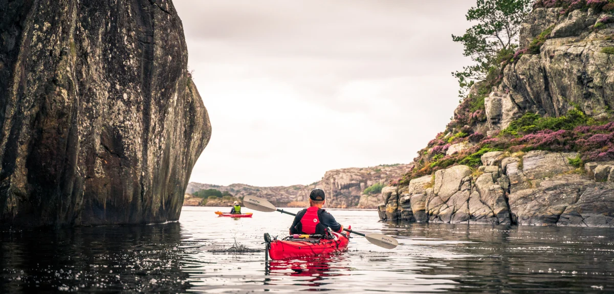 A man paddling in a red kayak