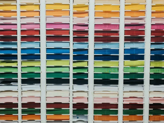 A shelf with sheets of paper in all the colors of the rainbow 
