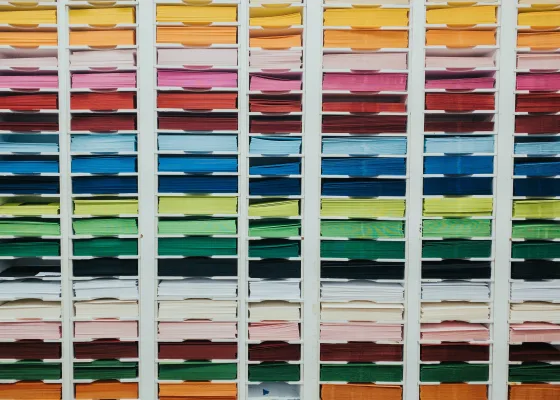 A shelf with sheets of paper in all the colors of the rainbow 