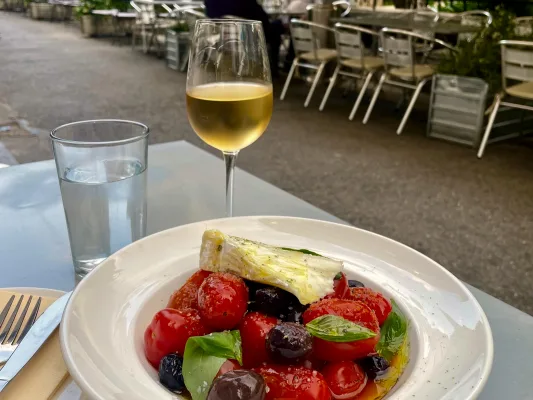 A rustic tomato salad with a glass of white wine