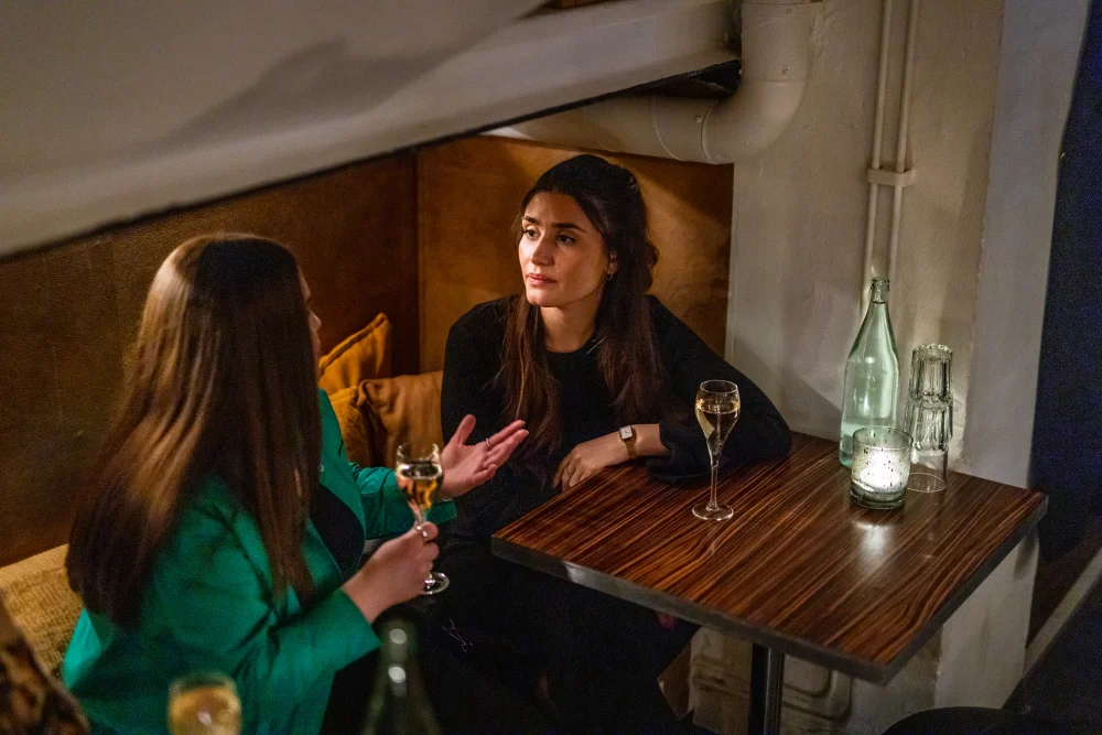 Two friends are conversing and drinking a glass of wine