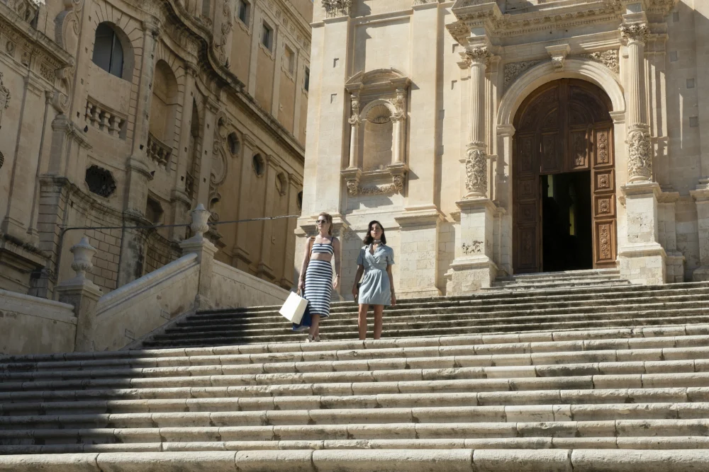 The White Lotus characters Daphne and Harper at the stairs of Noto Cathedral
