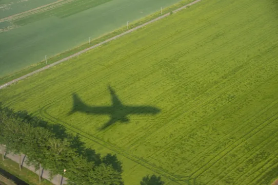 Flygplan på väg ner mot sommargrönska.