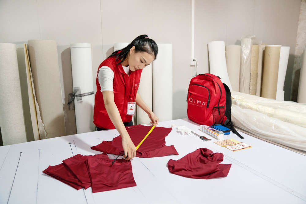 Garment quality inspection | QIMA – inspector measuring shirt