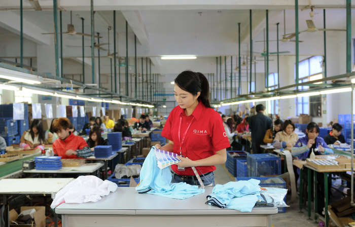 Garment quality control inspector checking color of shirt | QIMA 