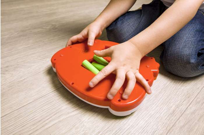 A child inserting batteries in plastic toy