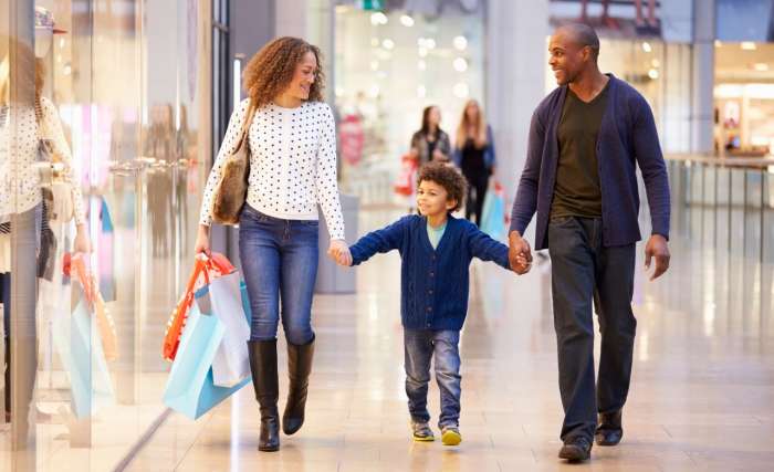 A man and woman holding hands in a shopping mall and walking with a child
