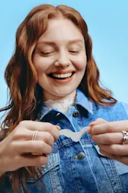Woman smiling after taking her blackhead pore strip off and looking at the results. 