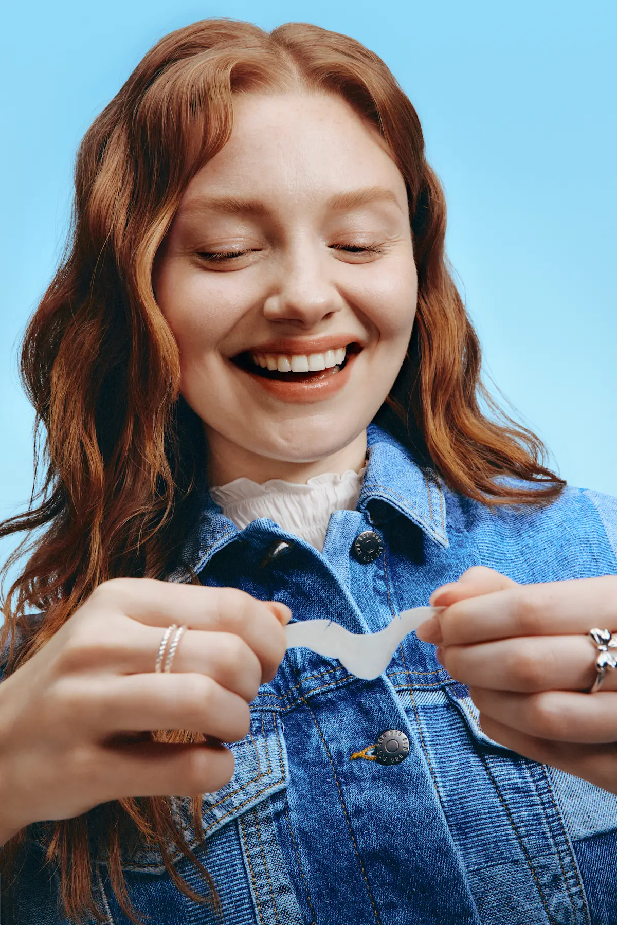 Woman smiling after taking her blackhead pore strip off and looking at the results.