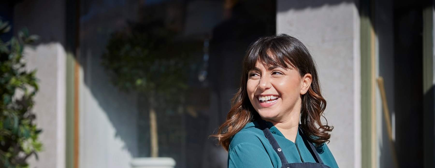 Laughing woman wearing an apron outside a café
