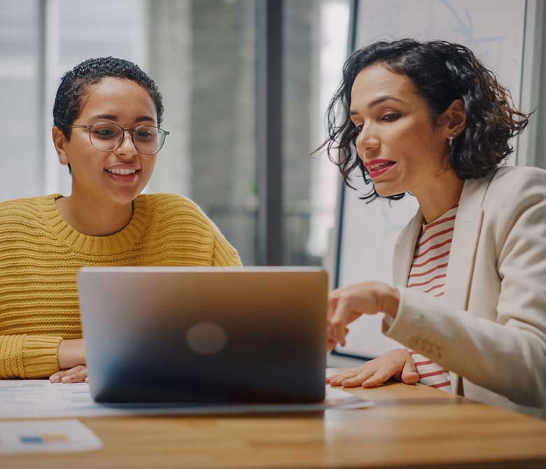 Two female colleagues sitting at laptop in mid discussion